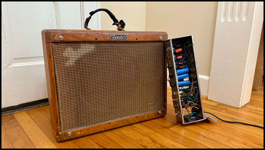 Front view of a vintage Fender 5E3 Tweed Deluxe cabinet with damaged chassis leaning beside it — part of a full amp restoration by Barbeaux Amplification.